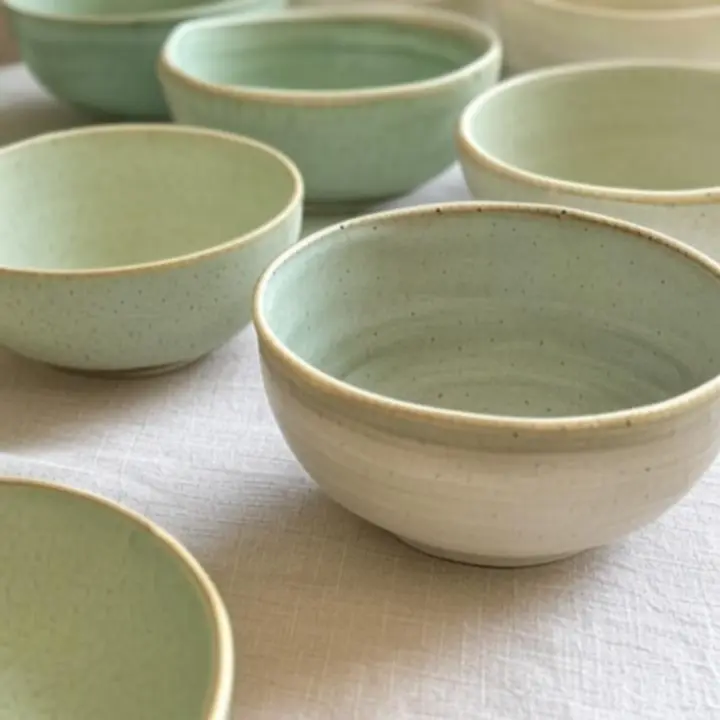 Kamionkowe miski w odcieniach szałwii i kremu ustawione na kuchennym blacie